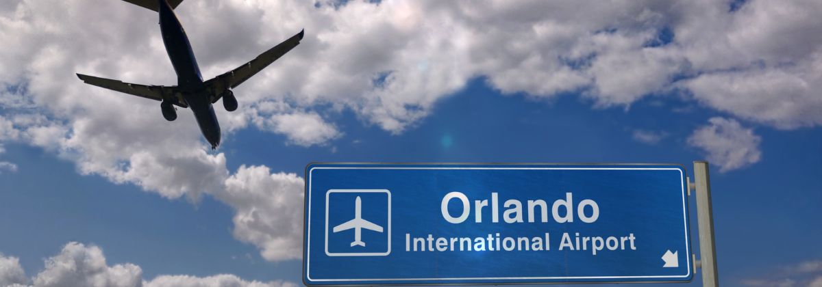 A plane flying over Orlando Airport sign 