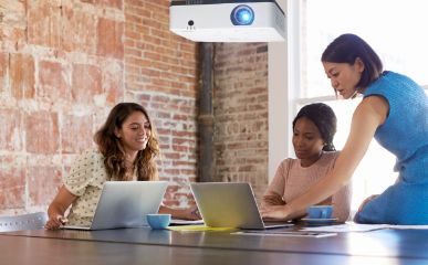 3 women in an office using a digital projector