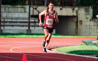 Strong runner jogging on athletic track on stadium