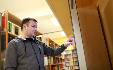 A man clicking a touchscreen AV in a library